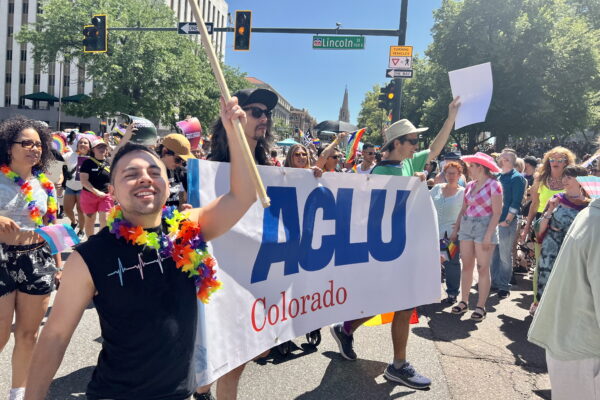 People in a march holding signs and rainbow flags