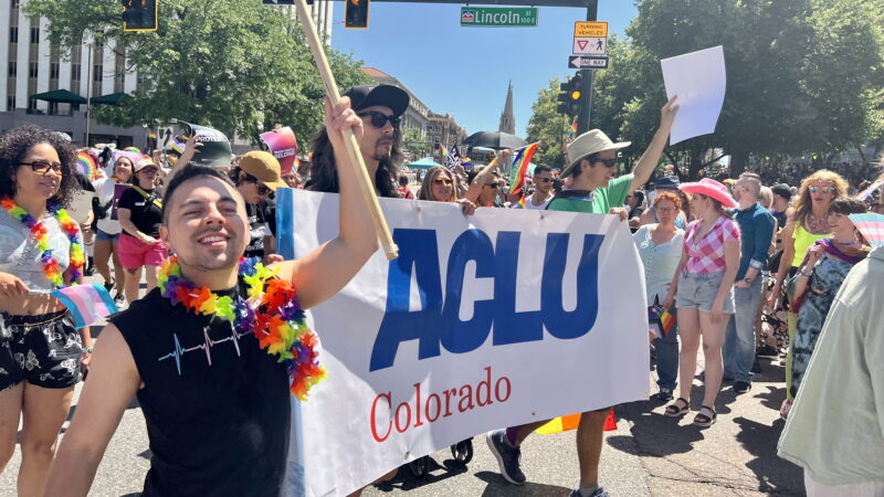 People in a march holding signs and rainbow flags
