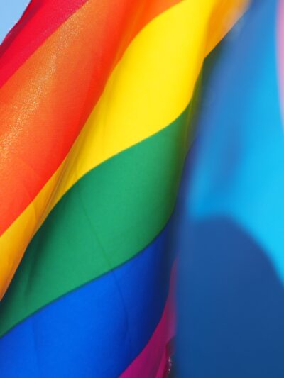photo of rainbow flag waving against a light blue sky