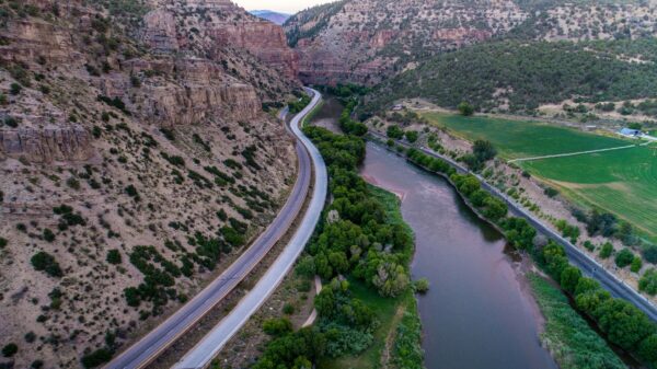 Photo of road stretching into the distance in between a cliff face and river