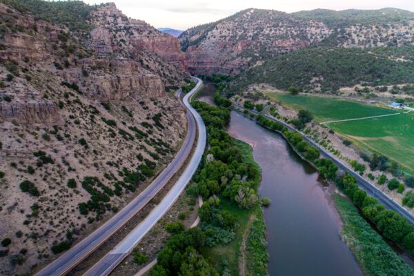 Photo of road stretching into the distance in between a cliff face and river