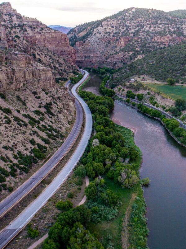 Photo of road stretching into the distance in between a cliff face and river
