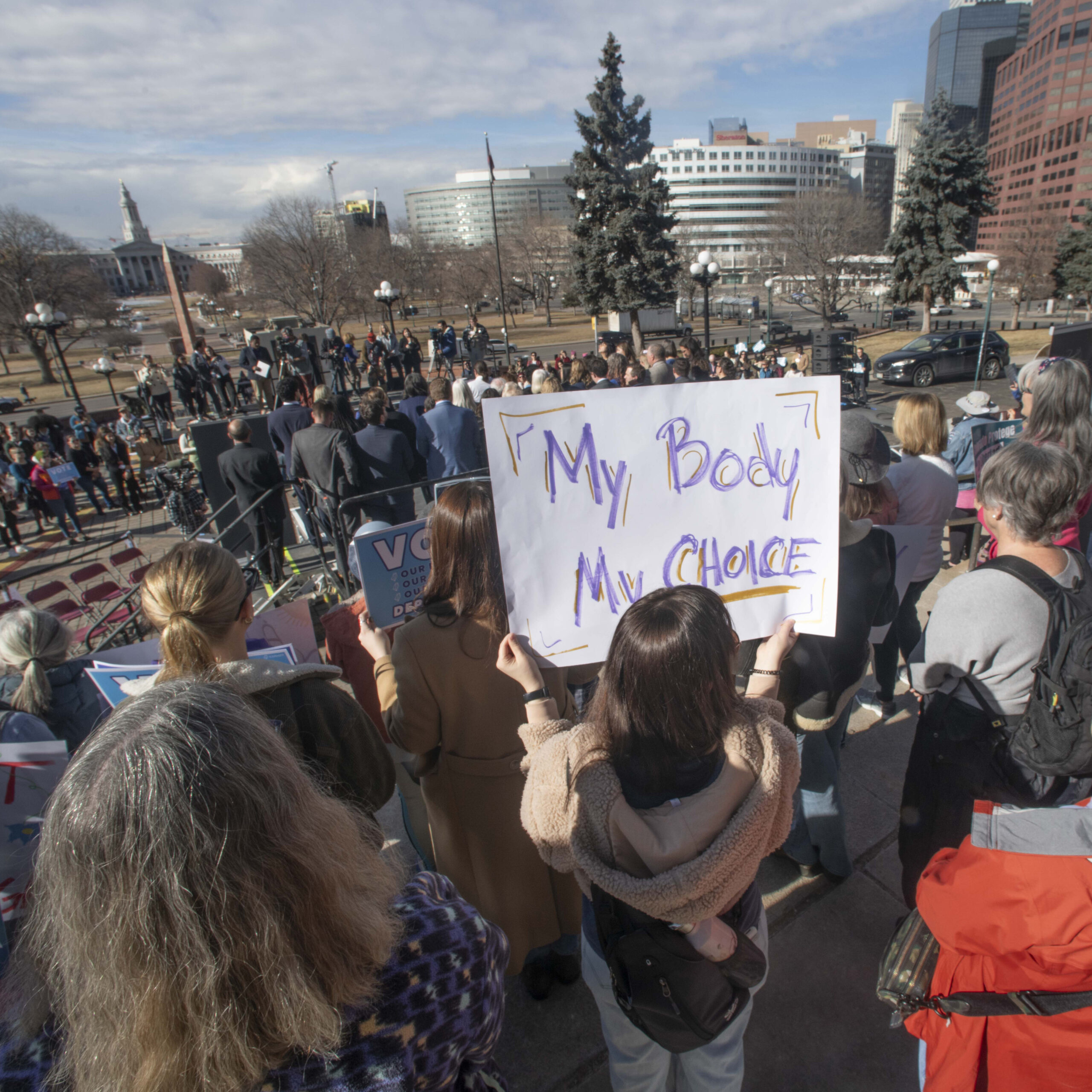 Photograph of protesters in a crowd with one person holding a sign with the text my body my choice