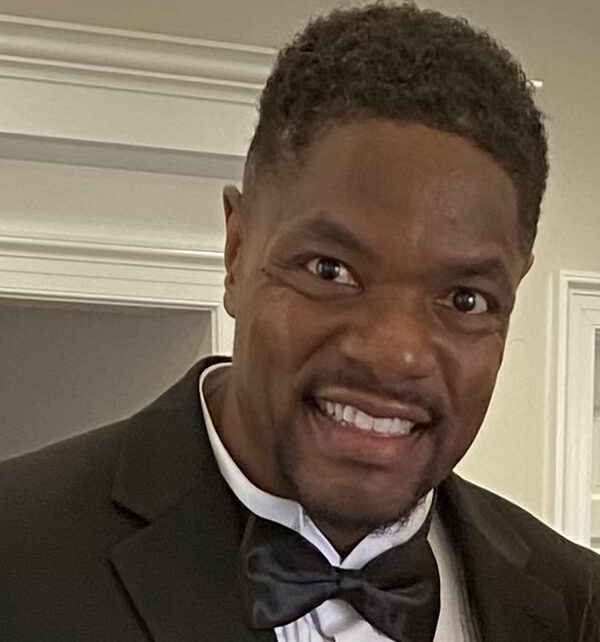 Headshot photo of Shawn Davis, smiling, standing in front of a doorway