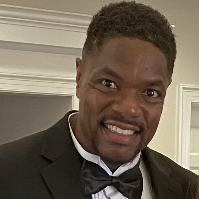 Headshot photo of Shawn Davis, smiling, standing in front of a doorway