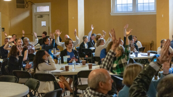 Photo of supporters at ACLU of Colorado's lobby day sitting around tables with their hands raised