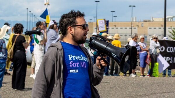 Julian Camera, ACLU of Colorado lead organizer, holds a megaphone at a protest