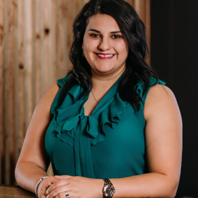Headshot photo of Elisa Thurston smiling in front of a light wood background