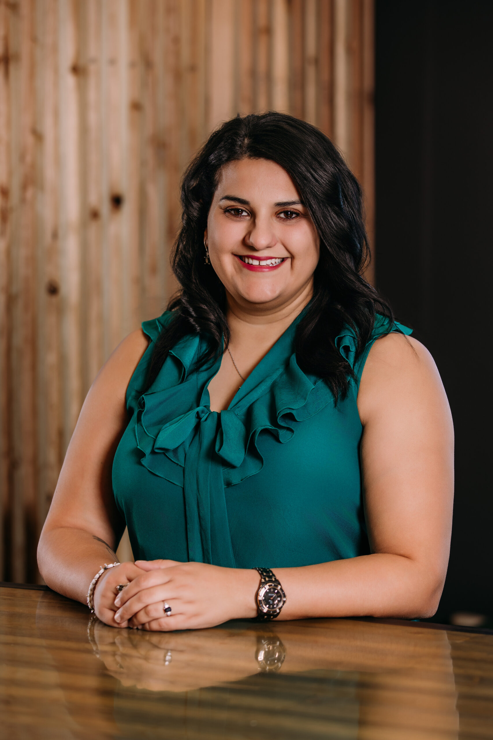 Headshot photo of Elisa Thurston smiling in front of a light wood background