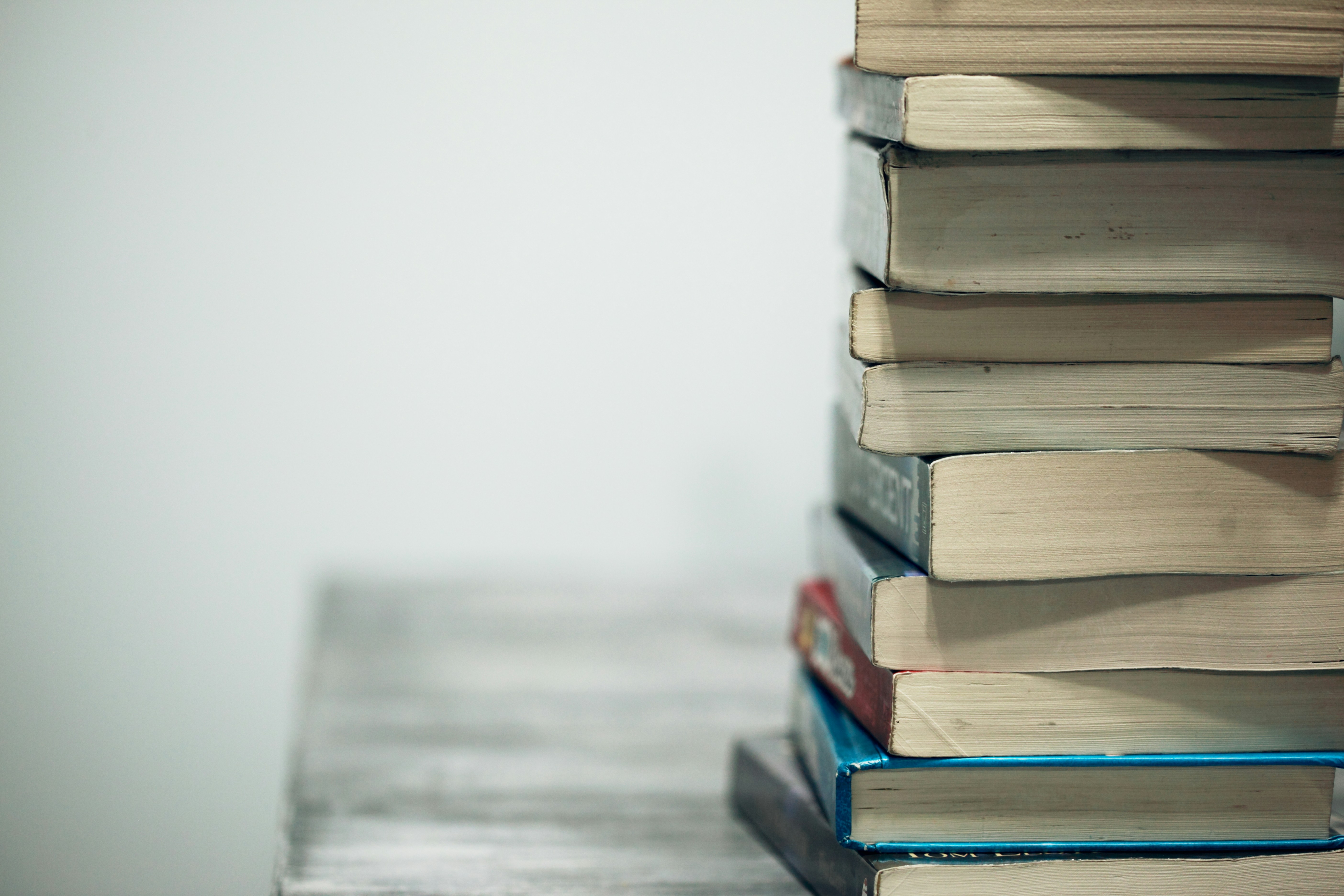 A stack of books on a table against a gray background