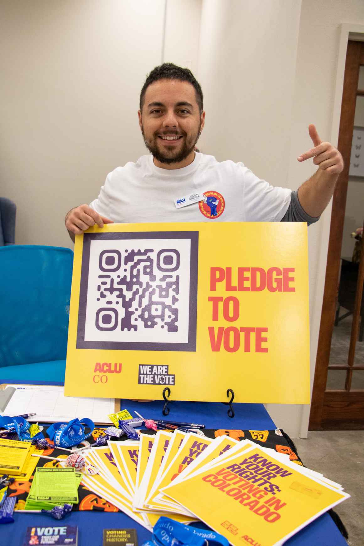 organizer holding poster with the text pledge to vote and a QR code
