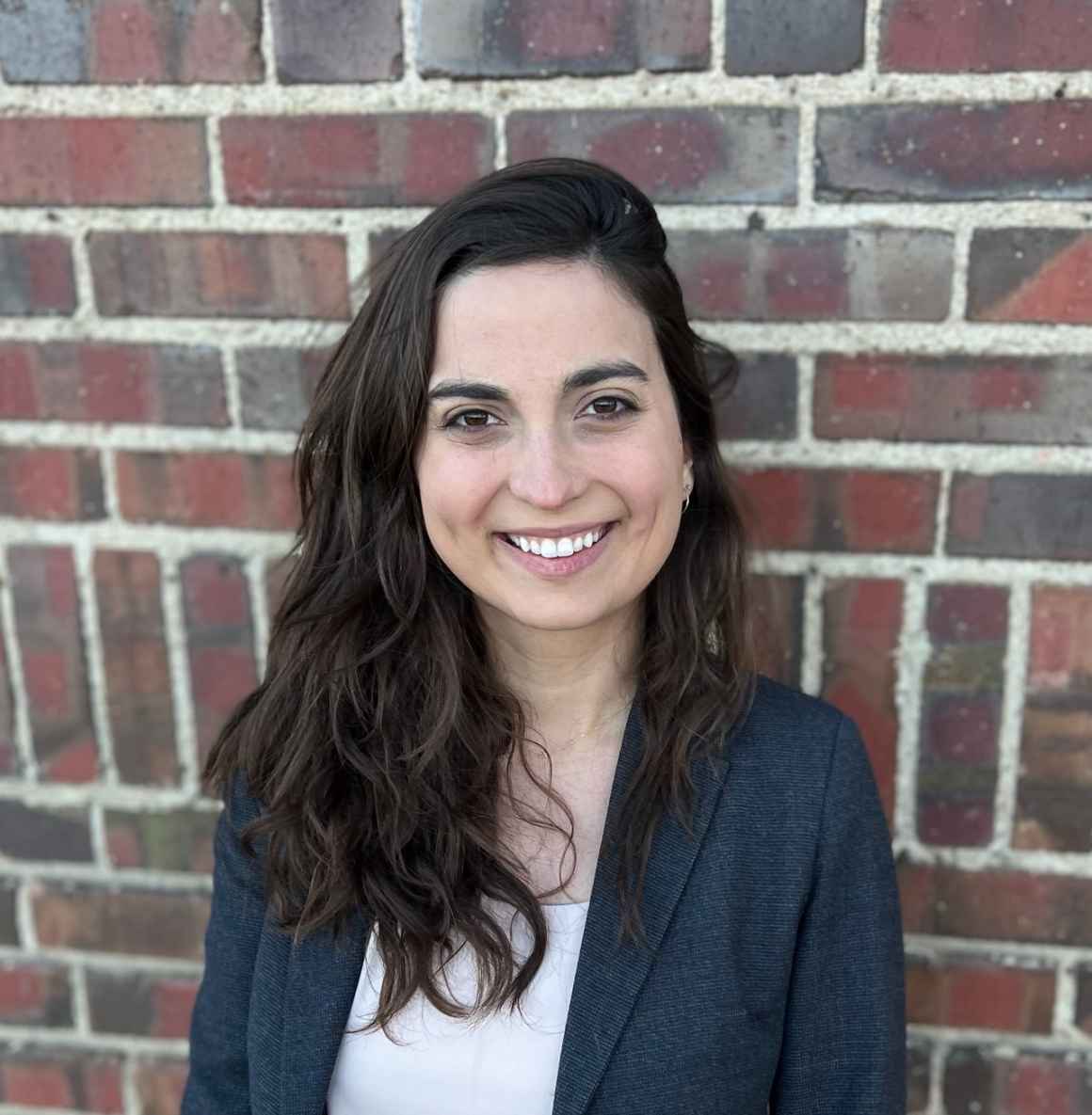 Cat Ordoñez, ACLU of Colorado Policy Counsel, smiling, in front of brick wall