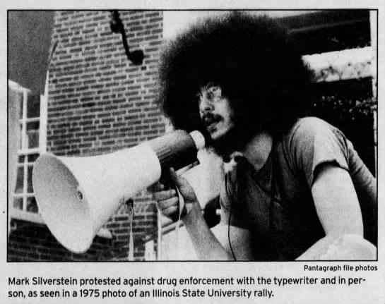 Photo of Mark Silverstein along with caption: Mark Silverstein protested against drug enforcement with the typewriter and in person, as seen in a 1975 photo of an Illinois State University Rally