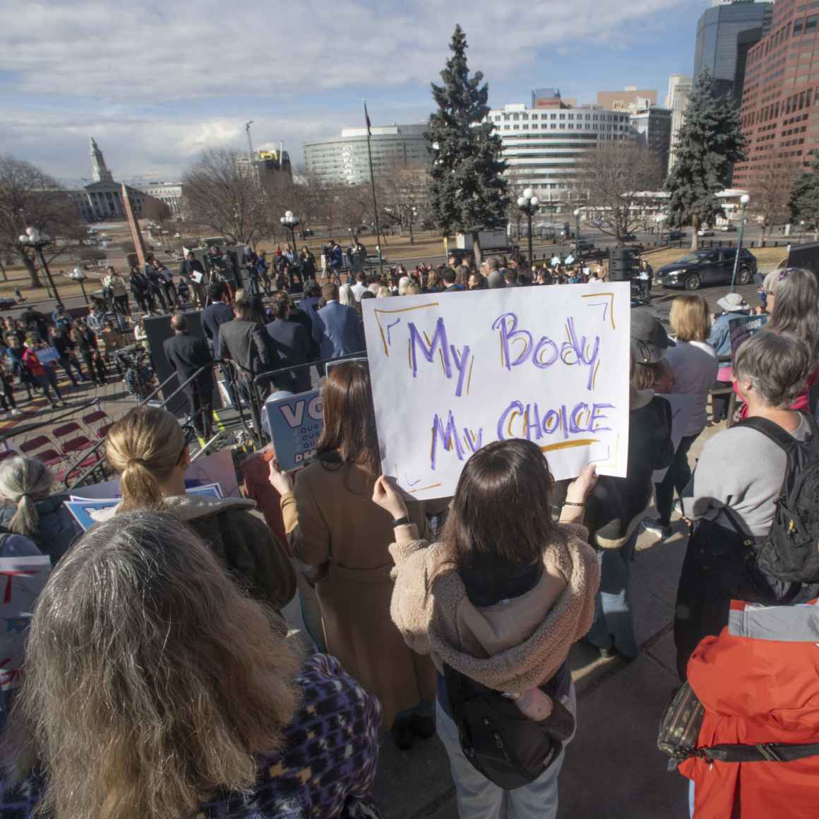 Photograph of protesters in a crowd with one person holding a sign with the text my body my choice