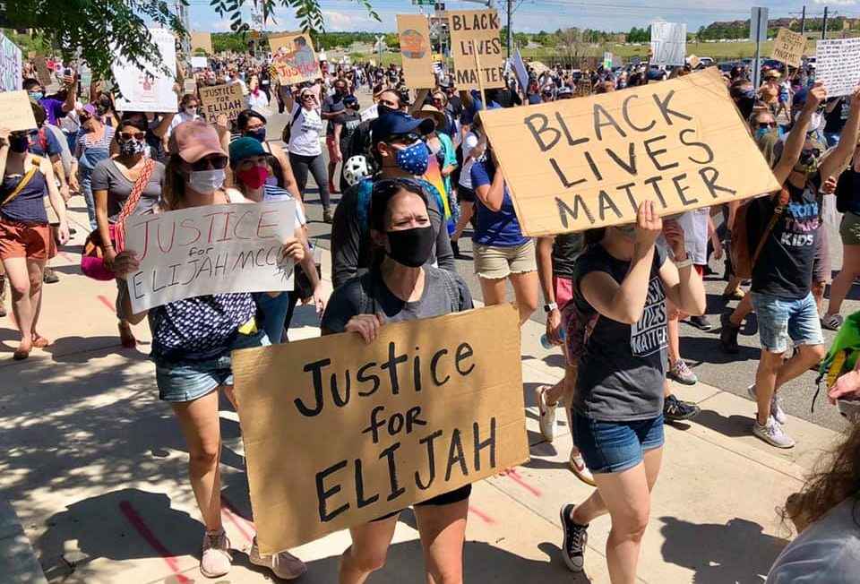 Photo of protesters marching with signs that say "Justice for Elijah" and "Black Lives Matter"