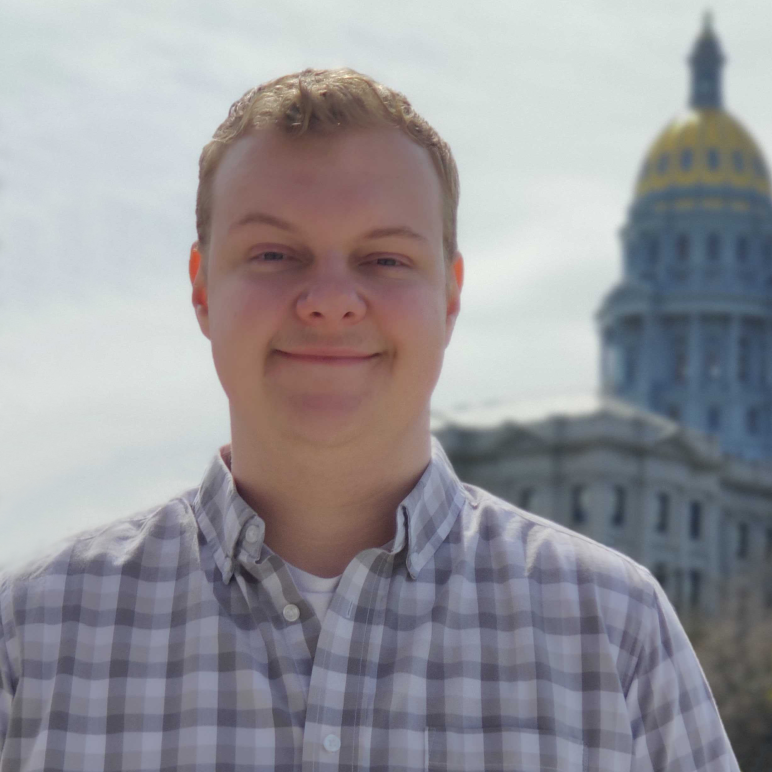 Portrait headshot of Ivan Popov standing in front of the Colorado State Capitol building