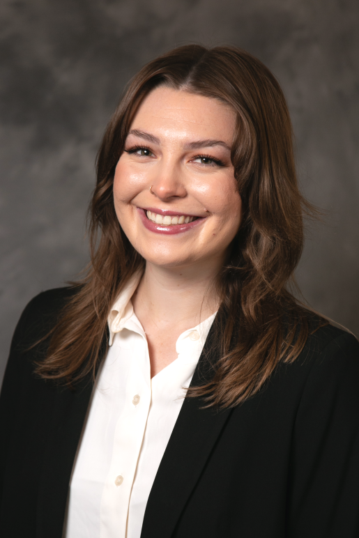 Sydney Poppe headshot photo, smiling, in front of gray background