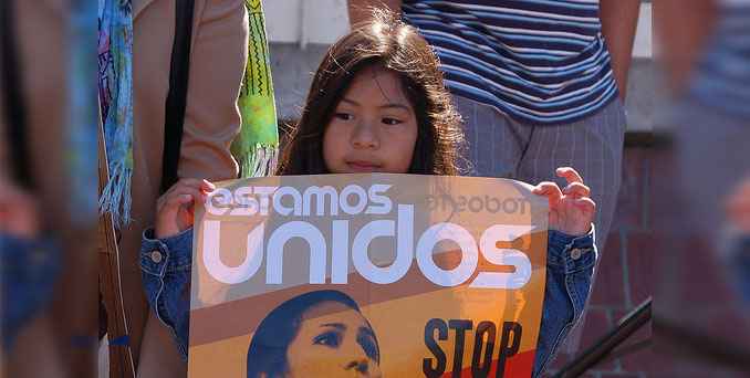 A child holds a sign that says "estamos unidos"