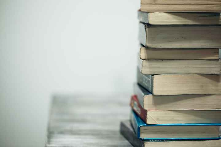 A stack of books on a table against a gray background