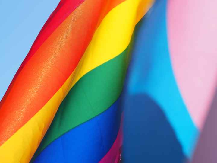 photo of rainbow flag waving against a light blue sky