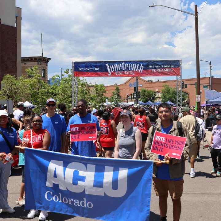 Photo of people in a parade holding a banner that says ACLU Colorado in front of a larger banner that says Juneteenth