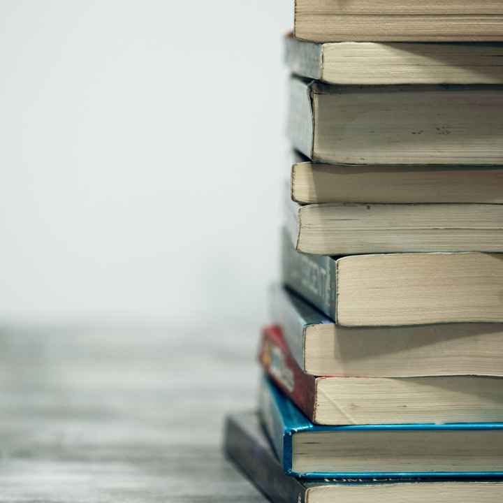 A stack of books on a table against a gray background